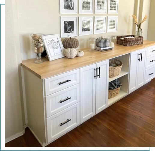 A white cabinet with wood top and drawers.